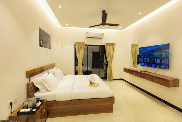 A hotel room with a bed, a TV, a ceiling fan, and a window with curtains.