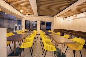A conference room with yellow chairs and tables, wooden ceiling, and large windows. - Coastal Cliff by ILIF Hotels (Murud)