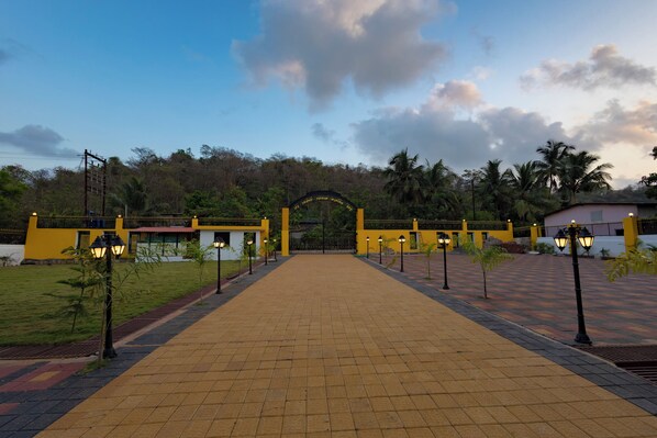 A paved pathway leading to a building with a yellow facade and a black archway.