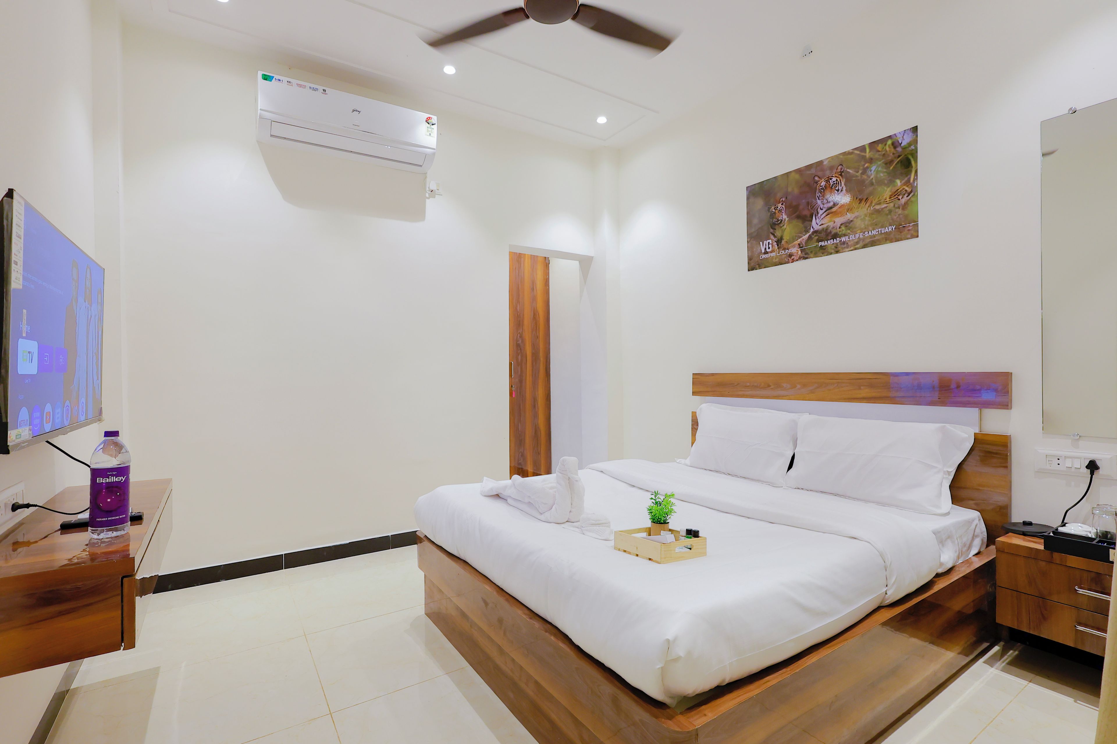 Una habitación de hotel con cama, mesita de noche, televisor y un cuadro en la pared.