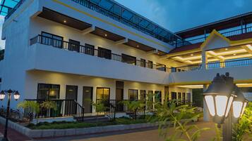 A multi-story hotel with a glass facade, outdoor lighting, and a paved courtyard.