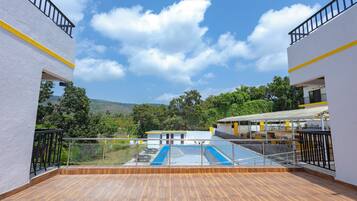 Una terraza en la azotea con piscina, rodeada de edificios con balcones.