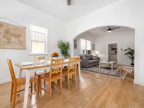 Uma sala de estar ampla com mesa de jantar, cadeiras, sofá e mesa de centro.