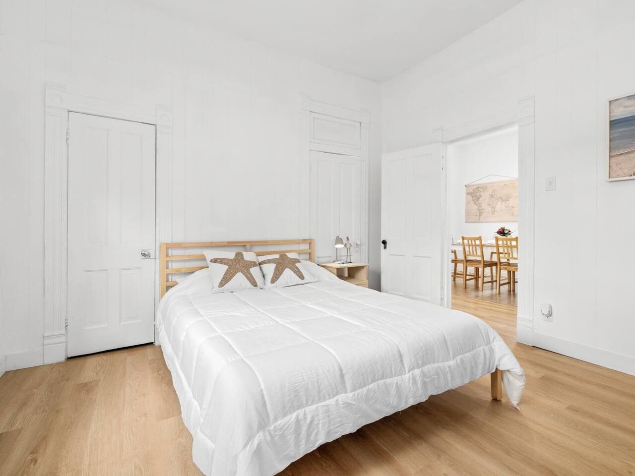 Ein Schlafzimmer mit einem Bett, einem hölzernen Kopfteil, weißen Wänden und einem Holzboden.