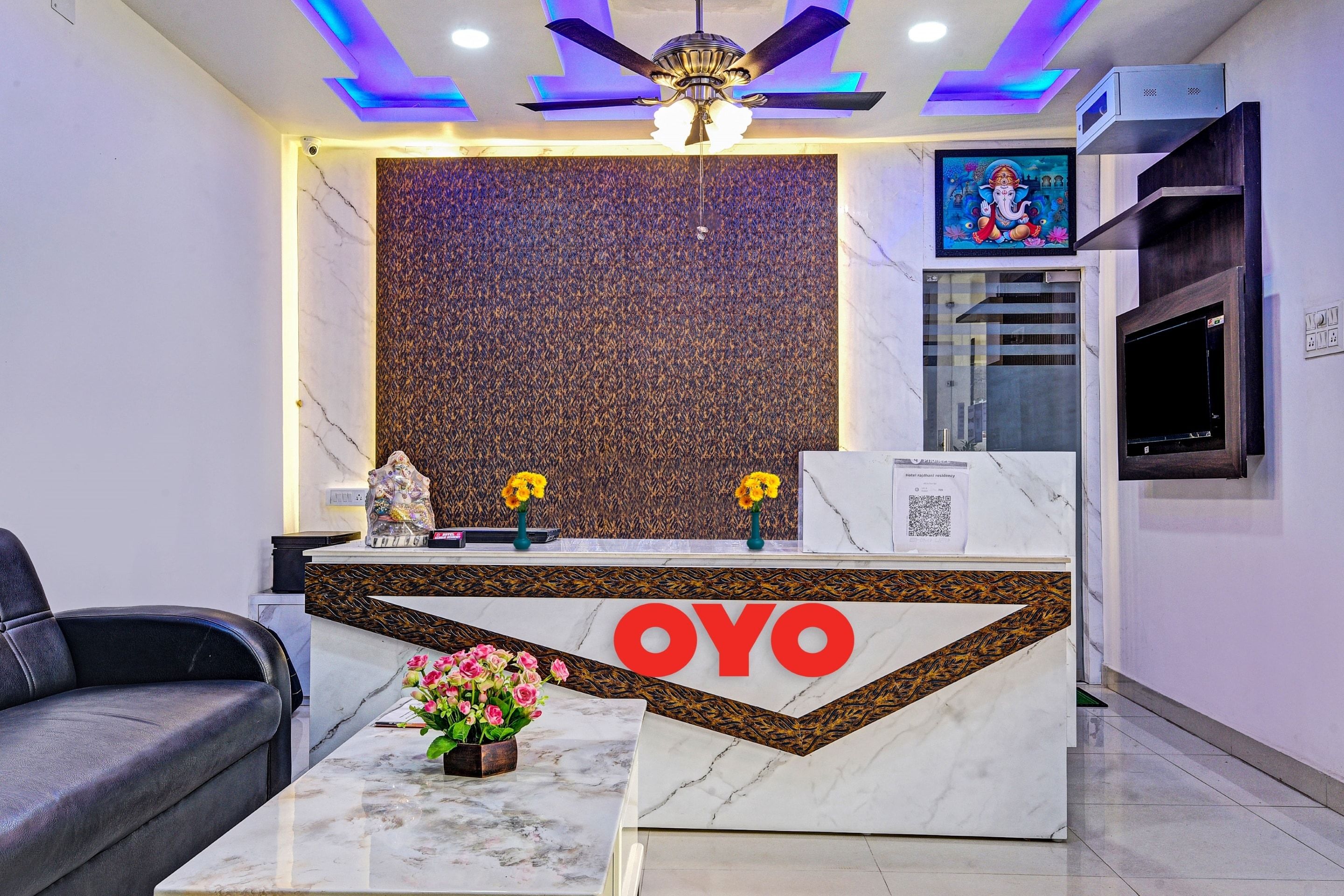 A reception desk with a marble top, a logo, and a decorative plant.