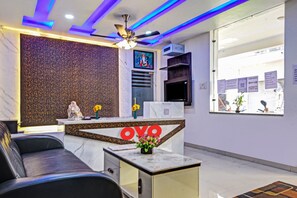 A reception area with a marble counter, a sofa, and a ceiling fan. - Hotel O Aura Hotel Rajdhani Residency (Ranchi)