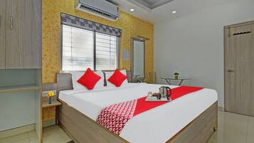A modern hotel room with a large bed, a bedside table, a small table with a plant, and a wardrobe.