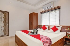 A hotel room with a bed, a wardrobe, a window with blinds, an air conditioning unit, and a decorative wall panel. - Hotel O Aura Hotel Rajdhani Residency (Ranchi)