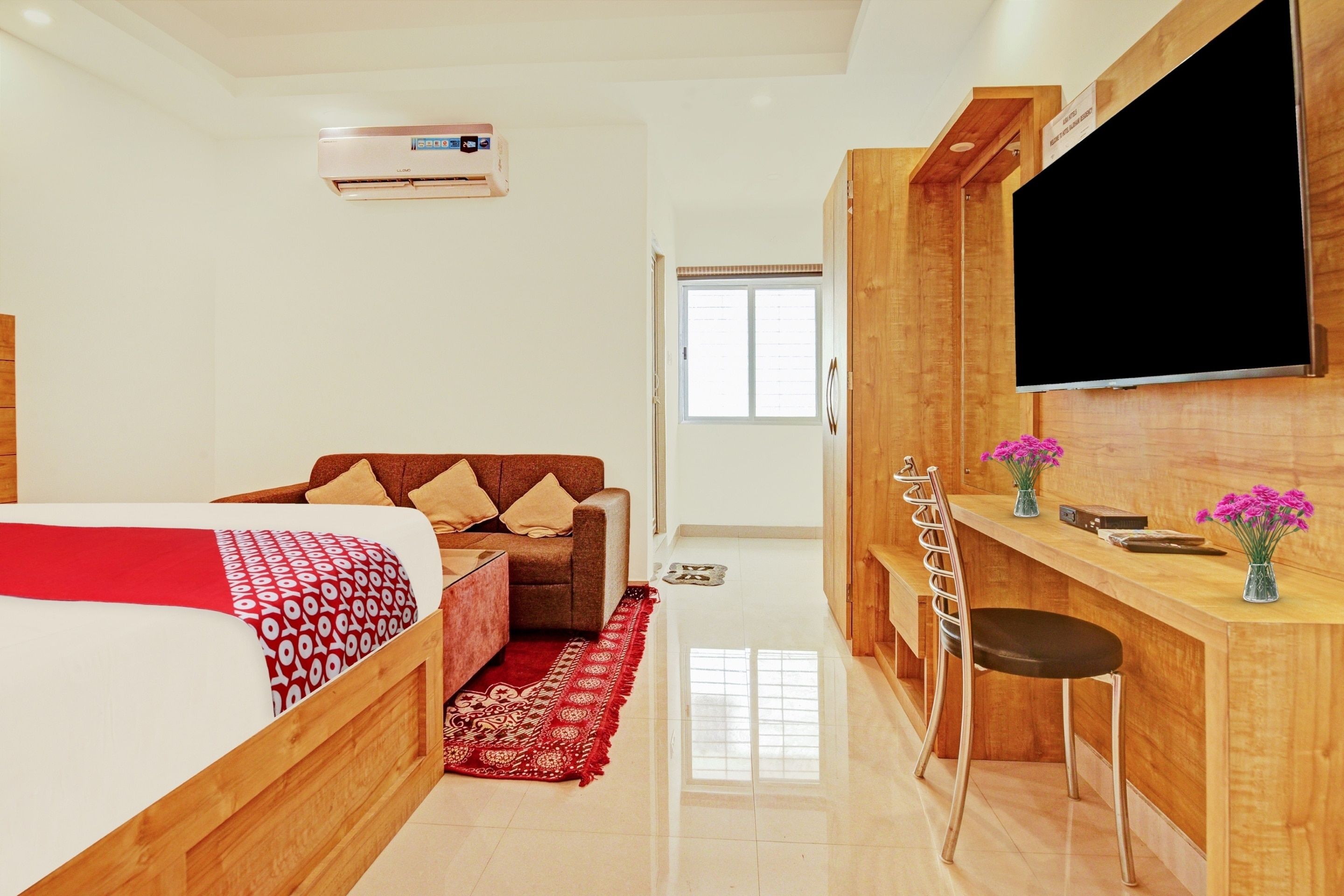 Habitación de hotel con cama, sofá, escritorio con silla, televisión y ventana.