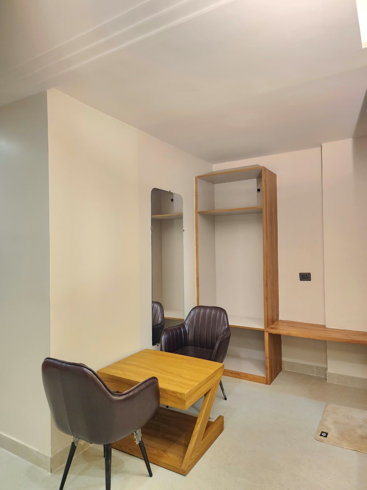 Una stanza dal design minimalista con un tavolo in legno, due poltrone in pelle ed elementi a scaffale integrati.
