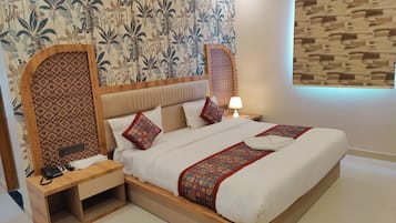 Una camera d'albergo con un letto grande, un comodino con telefono, una lampada e una parete decorata.