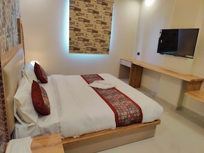 Habitación de hotel con cama, televisor, banco de madera y pared con diseño.