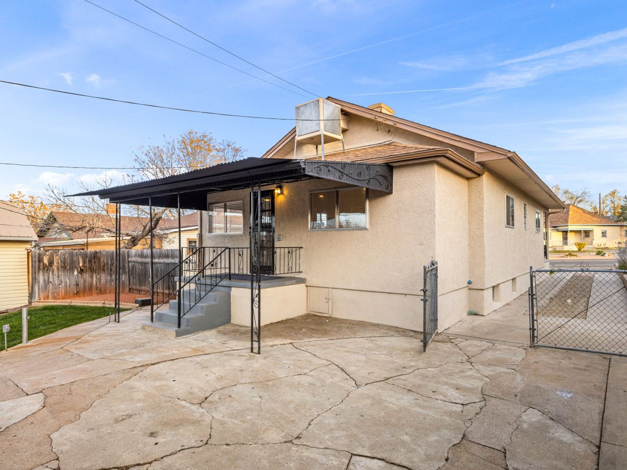 Propiedad residencial con un patio cubierto, una escalera que conduce a un segundo piso y un patio trasero cercado.