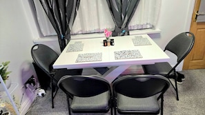 A dining table with four chairs, a vase with flowers, and a window with curtains. - A Cozy 2 bedroom apartment close to NEC & Airport (West Midlands)