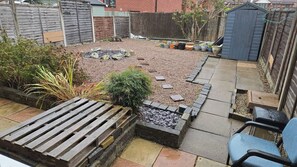 Ein Garten mit Kiesfläche, Holzterrasse und Kübelpflanzen.
