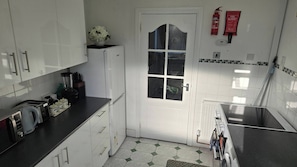 A kitchen with white cabinets, a black countertop, a coffee machine, and a fire extinguisher. - A Cozy 2 bedroom apartment close to NEC & Airport (West Midlands)