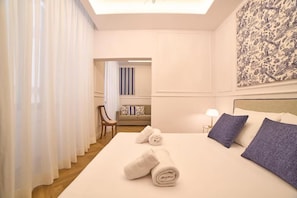 A hotel room with a bed, a nightstand, a lamp, a chair, and a view of the hallway. - Borgo 14 Residenza fiorentina (Florence)