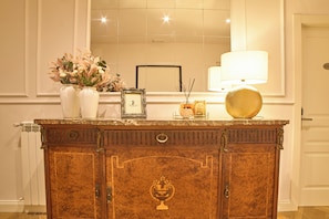 A wooden cabinet with a mirror above it, a vase with flowers, a framed picture, and a lamp. - Borgo 14 Residenza fiorentina (Florence)