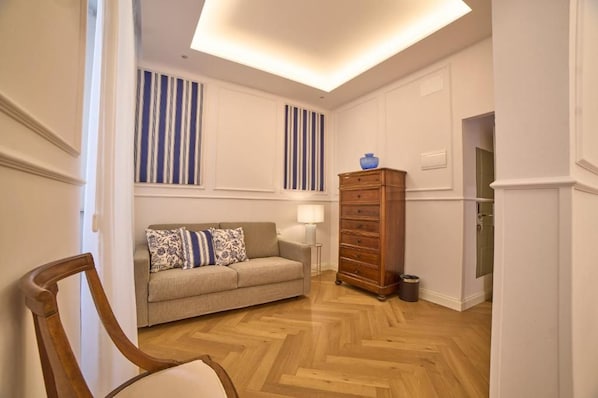 A room with a herringbone wooden floor, a sofa with patterned cushions, a wooden dresser, and a lamp. - Borgo 14 Residenza fiorentina (Florence)