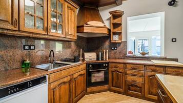 Una cocina con armarios de madera, horno empotrado y una ventana.