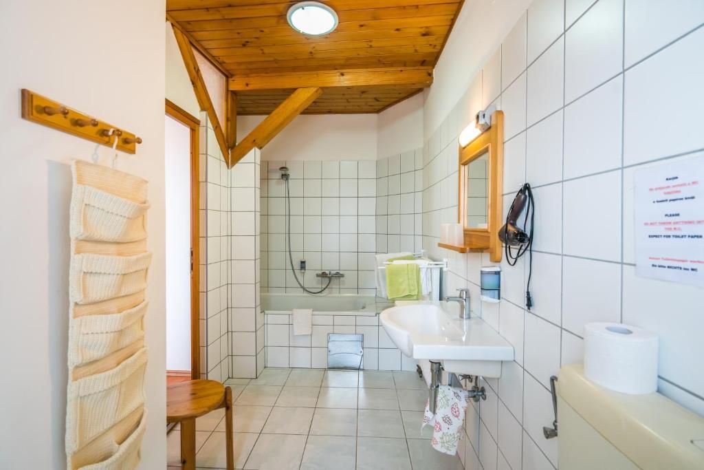 Un baño con techo de madera, ducha, lavamanos e inodoro.