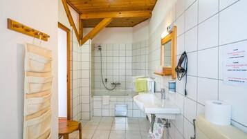 A bathroom with a wooden ceiling, a shower, a sink, and a toilet.