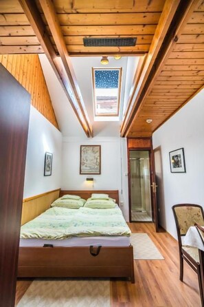 Une chambre à coucher avec un plafond en bois, un lit doté d’une tête de lit, une fenêtre et une porte.