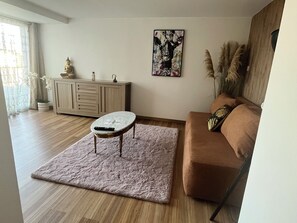 Una sala de estar con sofá, una mesa de centro, un armario y un cuadro.