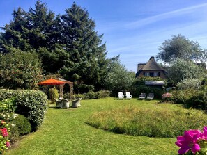A garden with a gazebo, outdoor seating, and a thatched-roof house. - Fabian Vacation Rental - 3-room vacation rental in Kampen for 5 people with a terrace, (Kampen (Sylt))
