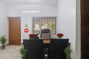 A conference room with a wooden door, a window with metal bars, a Lenovo laptop on a table, and two potted plants. - Super Hotel O Alpine Glow Crest (Hyderabad)