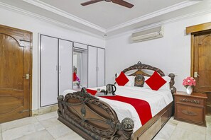 A bedroom with a wooden bed, a wardrobe, and a nightstand. - Super Hotel O Alpine Glow Crest (Hyderabad)