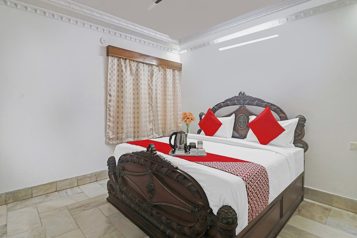 A neatly made bed with a decorative headboard, a ceiling fan, and a window with curtains.
