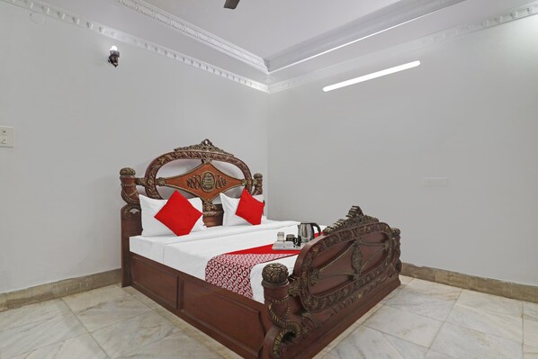 A neatly made bed with a wooden headboard, white bedding, and red pillows.