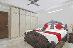 A bedroom with a large wardrobe, a bed with a decorative headboard, and a bedside table with a vase of flowers.