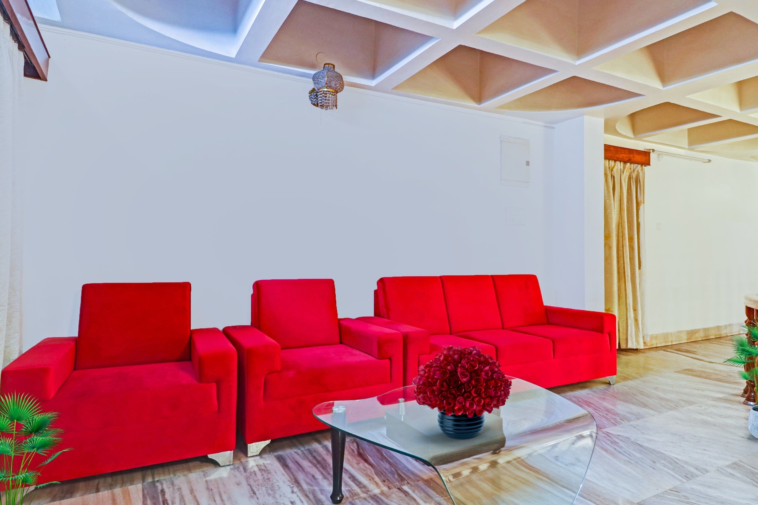 A modern living room with a red sofa set, a glass coffee table, and a decorative vase.
