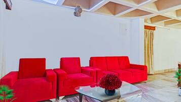 A modern living room with a red sofa set, a glass coffee table, and a decorative vase.
