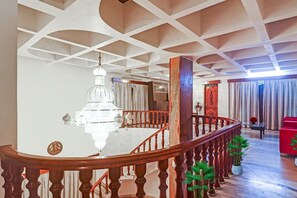 A spacious interior with a grand staircase, a chandelier, and a view of a room with a red sofa and curtains.