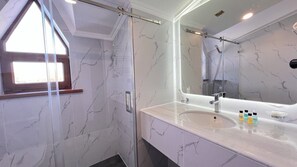 A bathroom with a shower, a sink with a mirror, and marble tiles. - hotel Kapriz Karakol (Karakol)