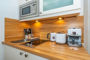 A compact kitchen with a microwave, toaster, and coffee maker on a wooden countertop. - Holiday apartment in Sylt with swimming pool (Sylt)