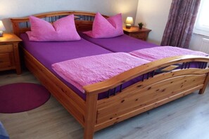 A double bed with a wooden frame and purple bedding. - Holiday apartment with 1 bedroom (Cuxhaven - Duhnen)