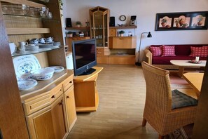 Ein gemütlicher Wohnraum mit Fernseher, Holzmöbeln und einem roten Sofa.