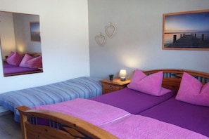 Een slaapkamer met twee bedden, een nachtkastje, een spiegel en een lijst met een afbeelding aan de muur.