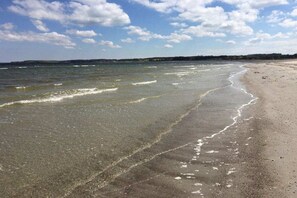 A beach with clear water, a sandy shore, and a distant shoreline. - Holiday apartment with 1 bedroom (Hohwacht)