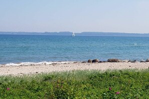 A beach with a sailboat in the distance, a sandy shore, and some rocks. - Holiday home in Langholz with barbecue (Langholz)