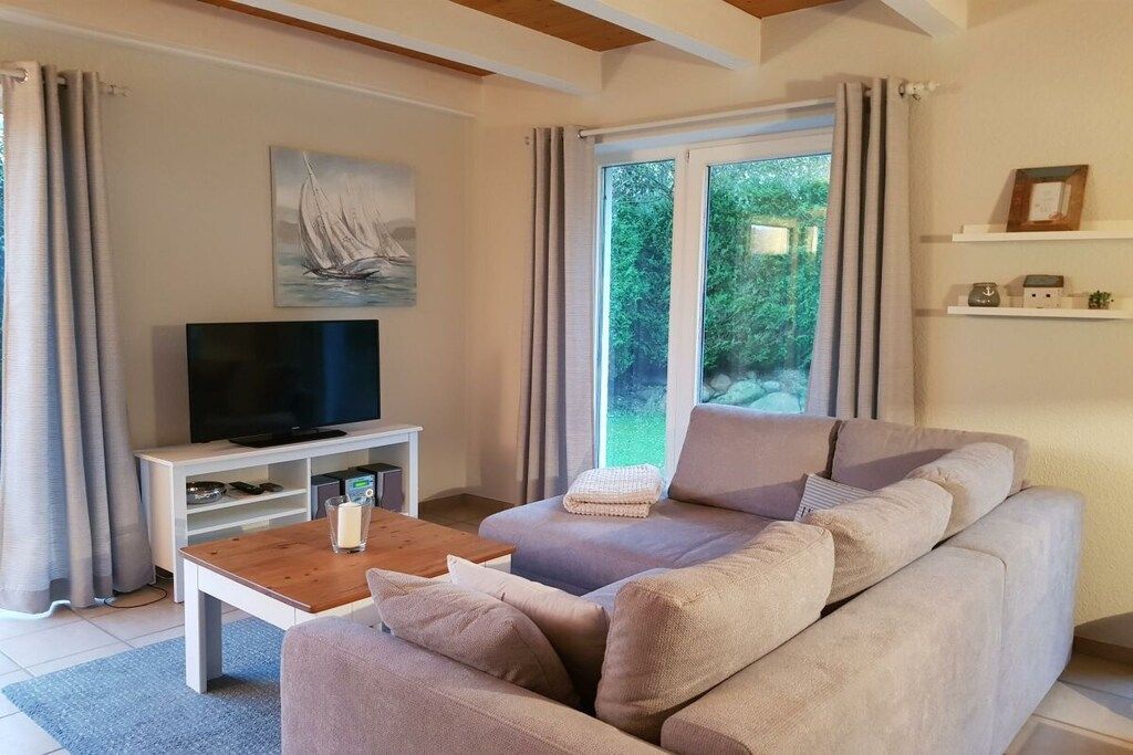 A living room with a sofa, a coffee table, a flat-screen TV, and a painting on the wall.