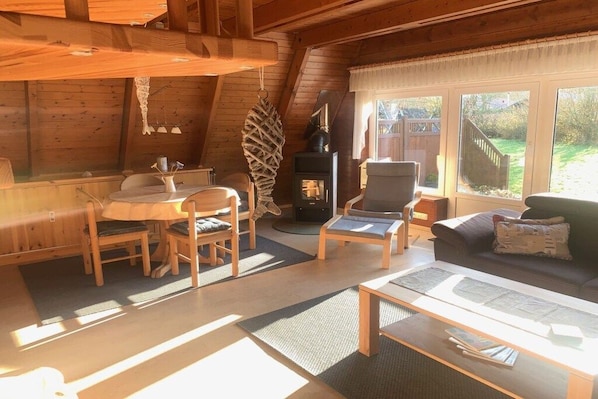 A cozy cabin interior with a dining area, a fireplace, and a sofa. - Holiday home in Damp with swimming pool (Damp)