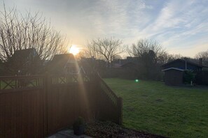A backyard with a wooden fence, a lawn, and a house in the background. - Holiday home in Damp with swimming pool (Damp)