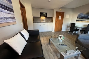 Ein moderner Wohnbereich mit einem Glastisch, einem schwarzen Sofa und einem grauen Sofa.