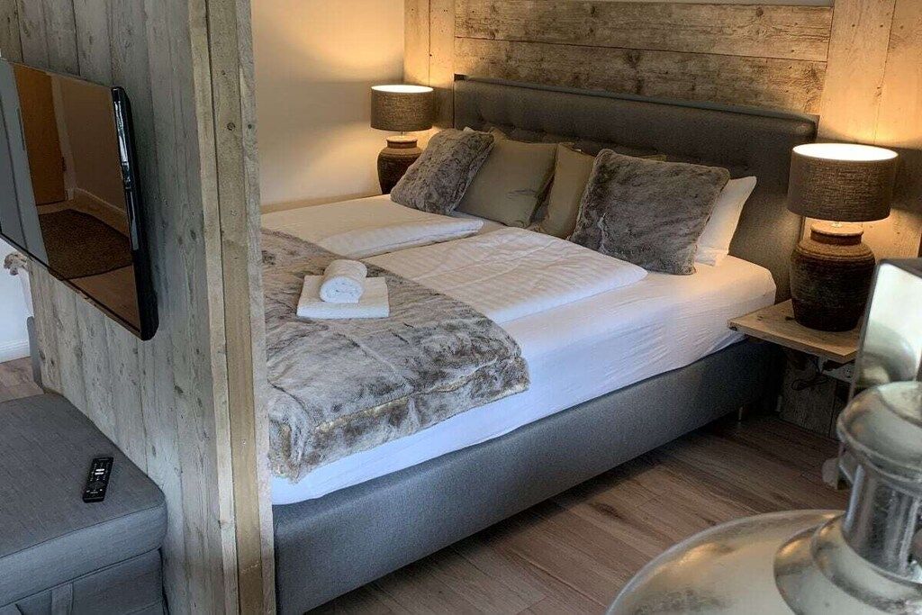 A bedroom with a bed, two bedside lamps, a mirror, and a small table.