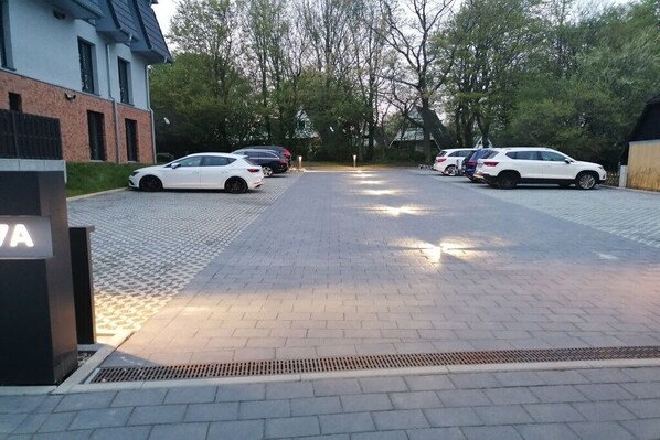 A parking area with multiple cars, a building with a sign, and trees in the background. - Holiday apartment in Damp with barbecue (Damp)